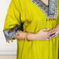 Yellow traditional outfit with intricate blue and white embroidery on a plain background
