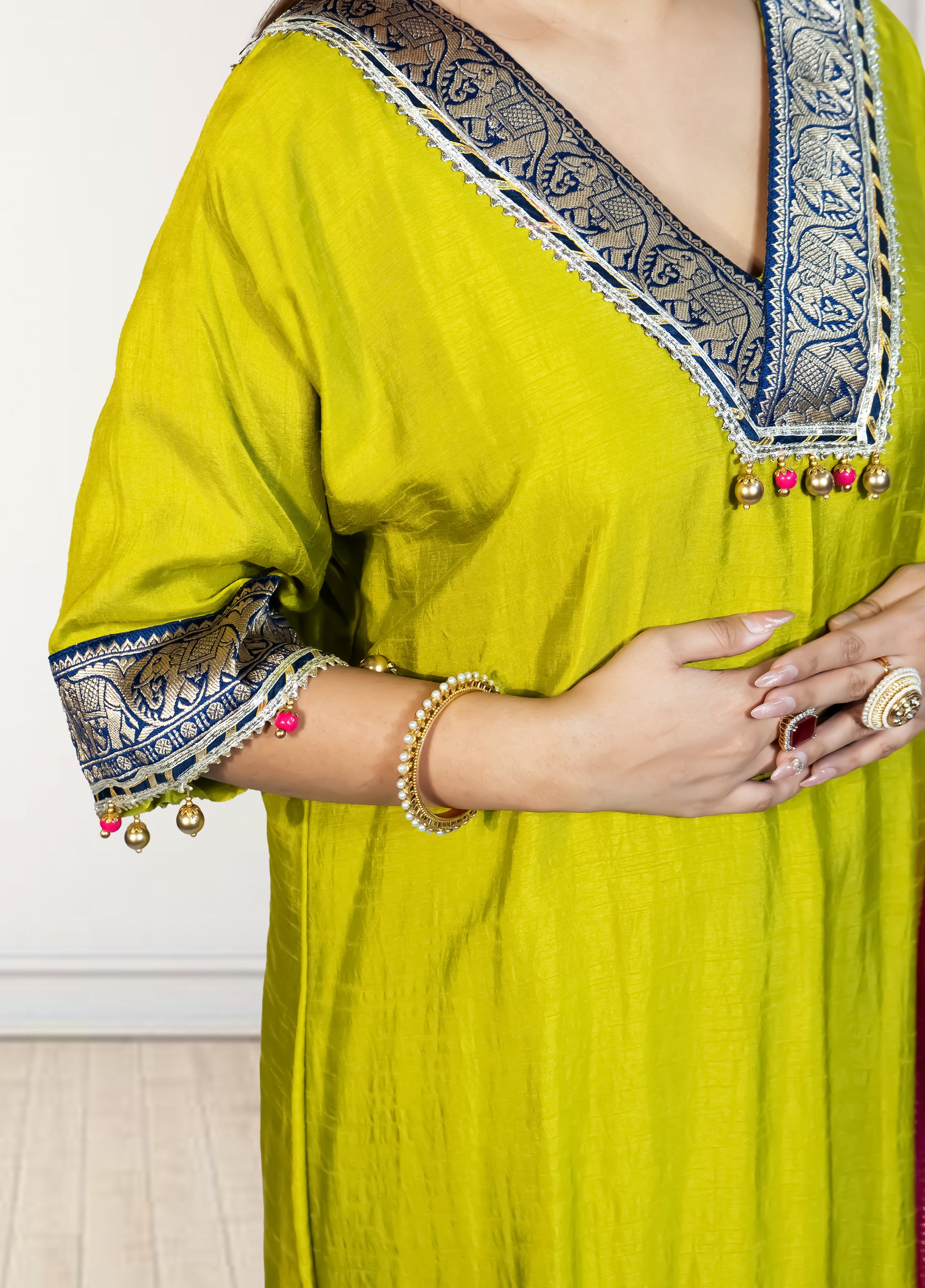 Yellow traditional outfit with intricate blue and white embroidery on a plain background