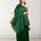 Woman wearing a green saree with a white wall background