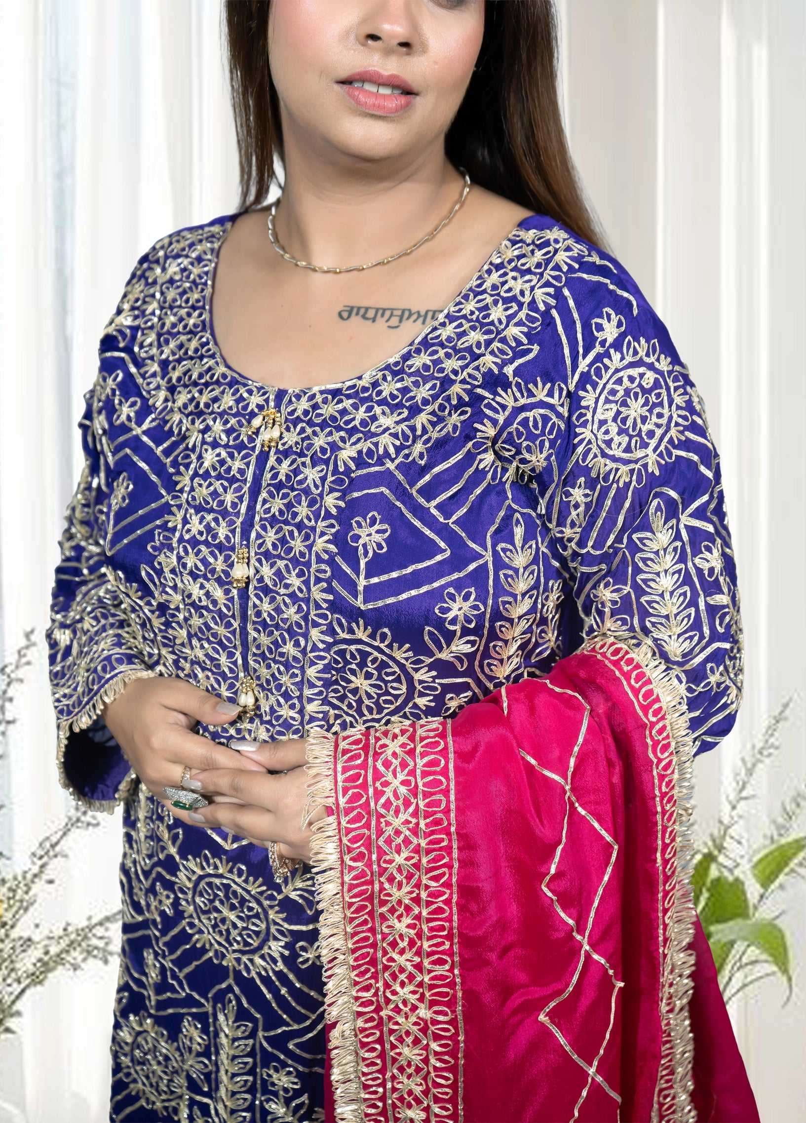Woman wearing a blue embroidered traditional outfit with a pink dupatta.