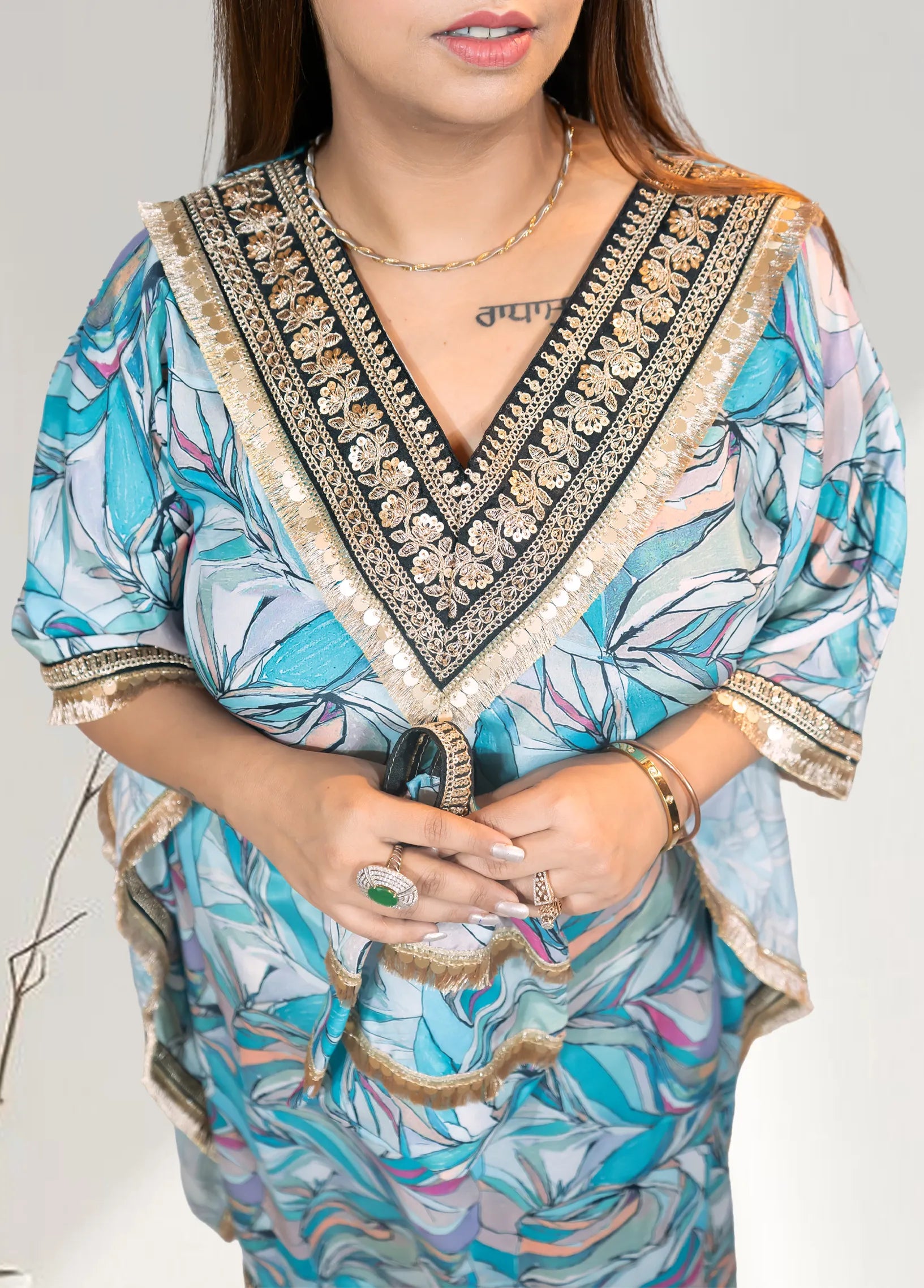 Woman wearing a blue floral dress with intricate embroidery on a plain background