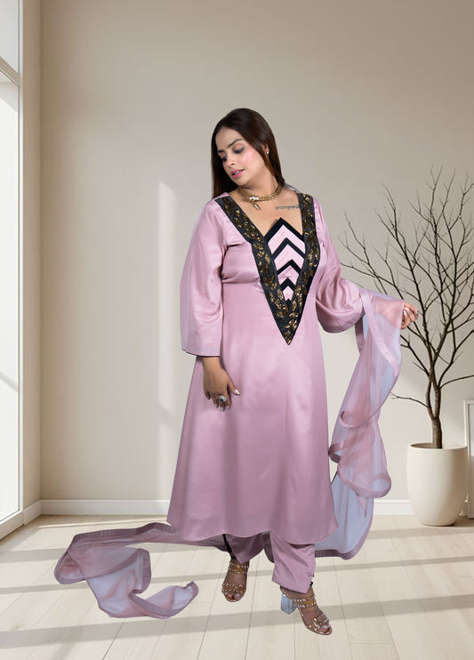 Woman wearing a pink traditional outfit with a black and white striped inner garment, standing in a room with a neutral color scheme.