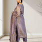 Woman wearing a traditional outfit with a long purple dupatta in a minimal indoor setting