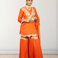 Woman wearing an orange traditional outfit with white embroidery on a plain background