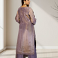 Woman wearing a long, light purple dress with a sheer overlay in a minimal indoor setting.