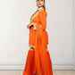 Woman wearing an orange saree with gold border on a white background