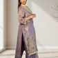 Woman wearing a traditional outfit with intricate designs indoors.