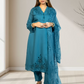 Woman wearing a blue embroidered outfit in a minimal indoor setting