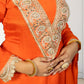 Orange traditional outfit with intricate gold embroidery on a plain background