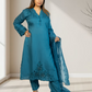 Woman wearing a teal embroidered outfit with a matching dupatta in a well-lit room.