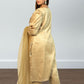 Woman wearing a gold traditional outfit with a plain background