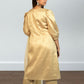 Woman wearing a gold traditional outfit with a plain background