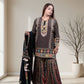 Woman wearing a traditional outfit with intricate patterns in a well-lit room.