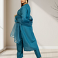Woman wearing a blue traditional outfit in a minimalistic room.