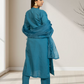 Woman wearing a blue traditional outfit in a minimalistic room.