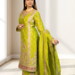 Woman wearing a green embroidered traditional outfit in a bright room.