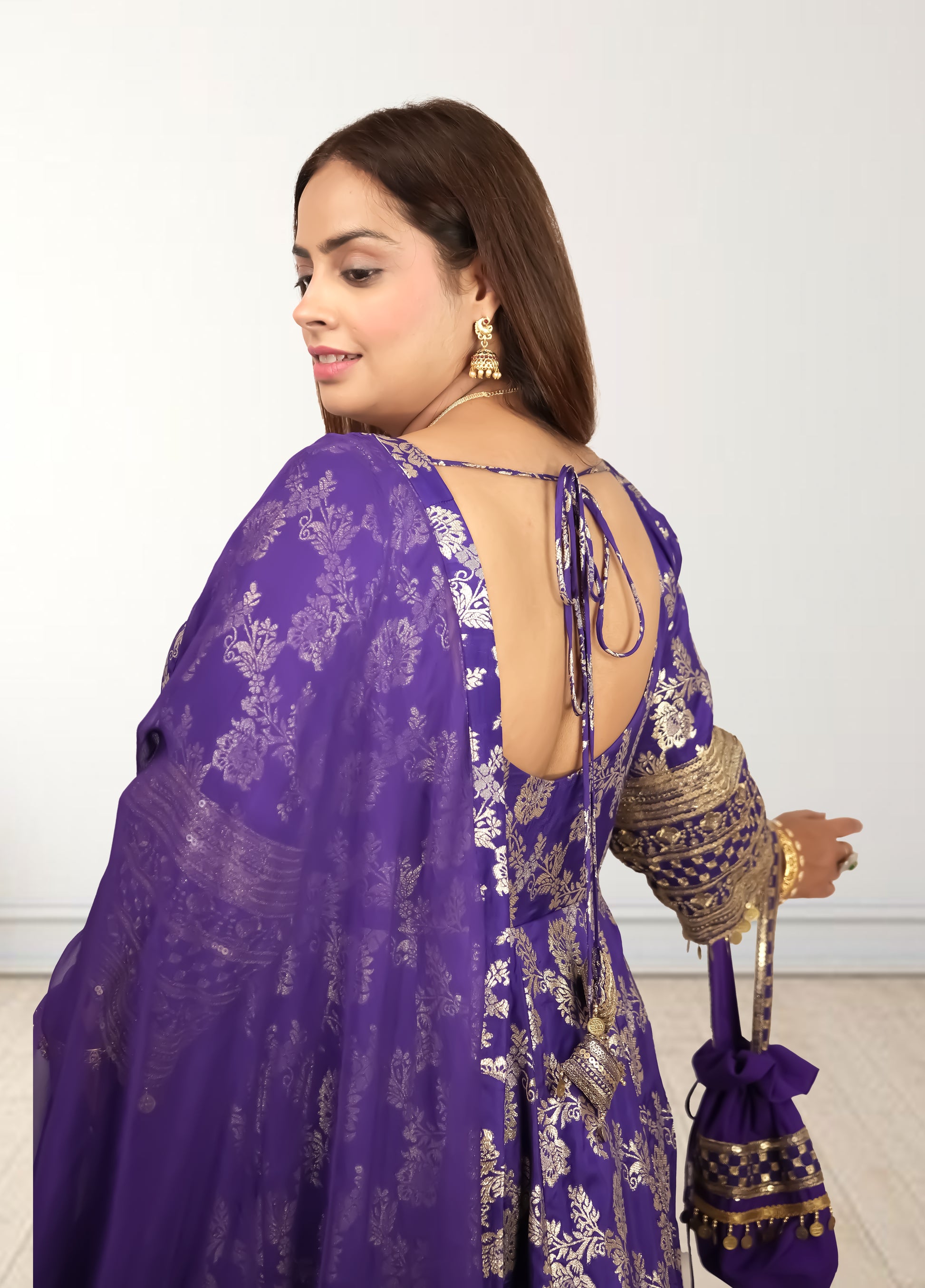 Woman wearing a purple traditional outfit with gold embroidery on a white background