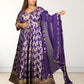 Woman wearing a traditional purple and gold outfit with a matching dupatta on a white background