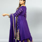 Woman wearing a purple traditional outfit with gold embroidery on a plain background