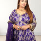 Woman wearing a purple embroidered traditional outfit with gold details on a white background
