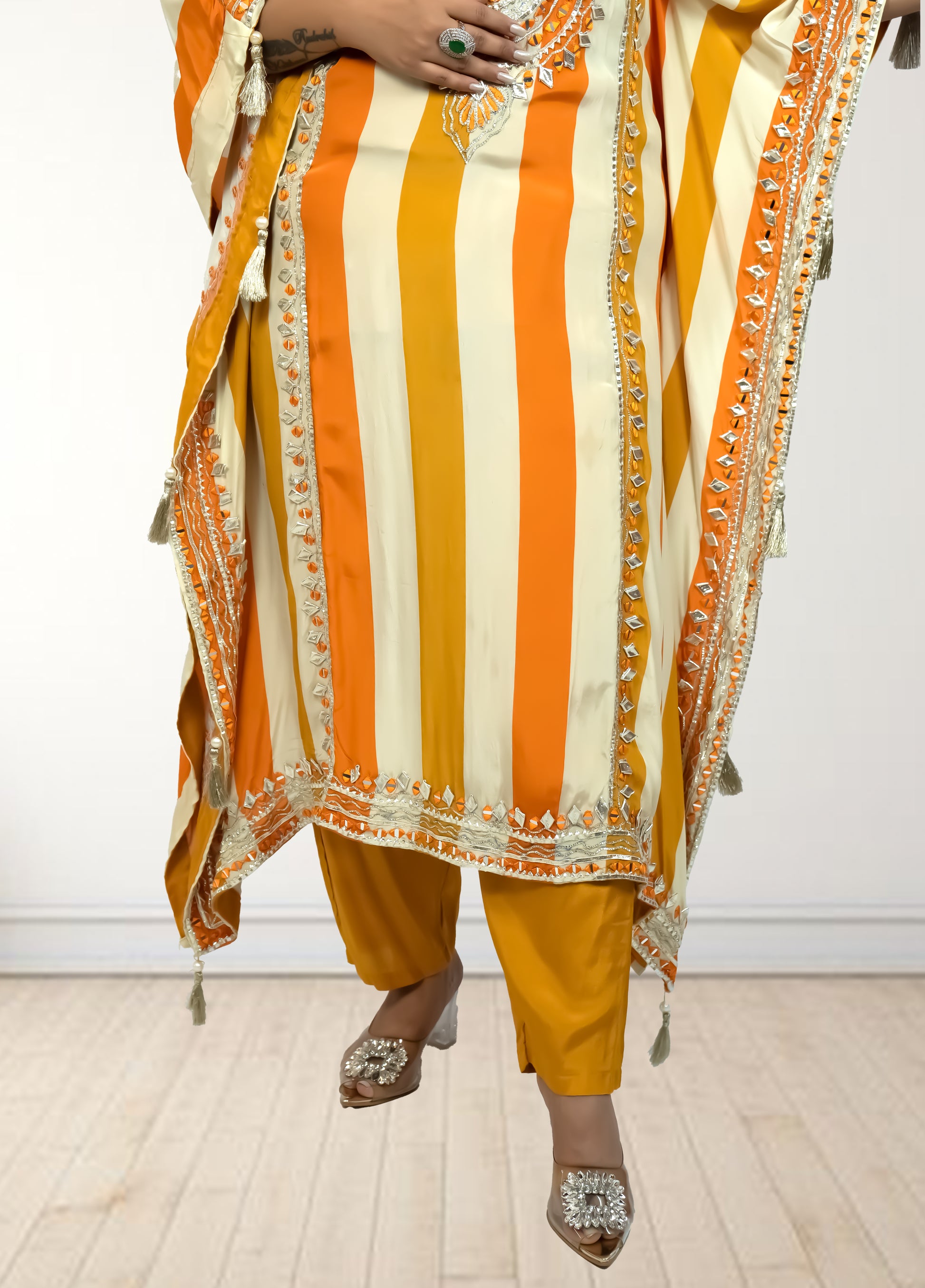 Person wearing a traditional outfit with orange and yellow stripes on a white background