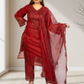 Woman wearing a red traditional outfit with a matching dupatta in a minimal indoor setting.