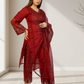 Woman wearing a red traditional outfit with lace details in a minimal indoor setting.