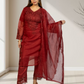 Woman wearing a red traditional outfit with a sheer dupatta in a minimal indoor setting