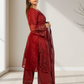Woman wearing a red embroidered outfit standing in a well-lit room.