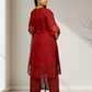 Woman wearing a red traditional outfit standing in a minimalistic room.