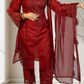 Red embroidered traditional outfit with a matching dupatta held by a person indoors.