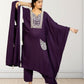 Woman wearing a purple traditional outfit with white embroidery against a plain background