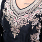 Black garment with intricate white embroidery on a dark background