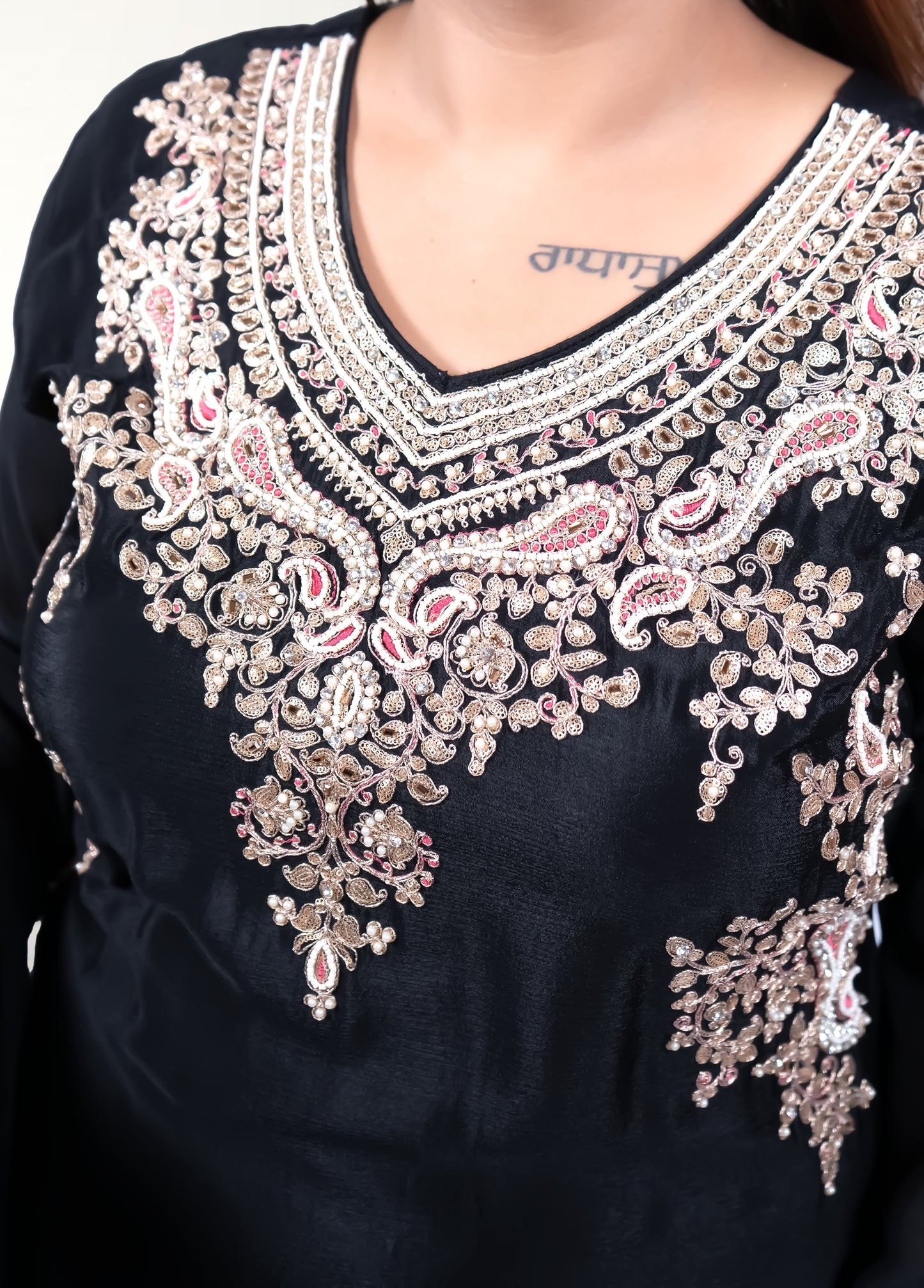 Black garment with intricate white embroidery on a dark background