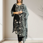 Woman wearing a black floral embroidered outfit with a matching dupatta in a minimal indoor setting.