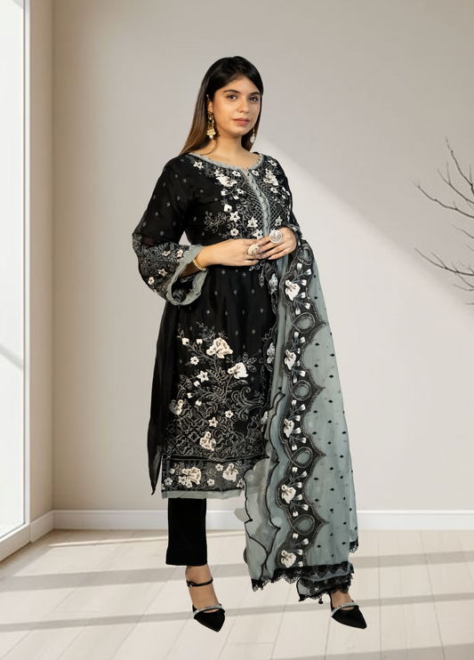 Woman wearing a black embroidered outfit with a matching dupatta in a minimal indoor setting