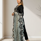 Woman wearing a black outfit with a sheer, embroidered dupatta in an indoor setting