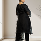 Woman wearing a black outfit with sheer sleeves and bottom hem in a minimal indoor setting