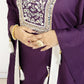 Purple traditional outfit with intricate white embroidery and tassels on a plain background