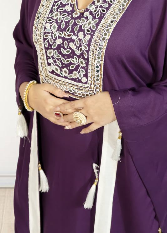 Purple traditional outfit with intricate white embroidery and tassels on a plain background