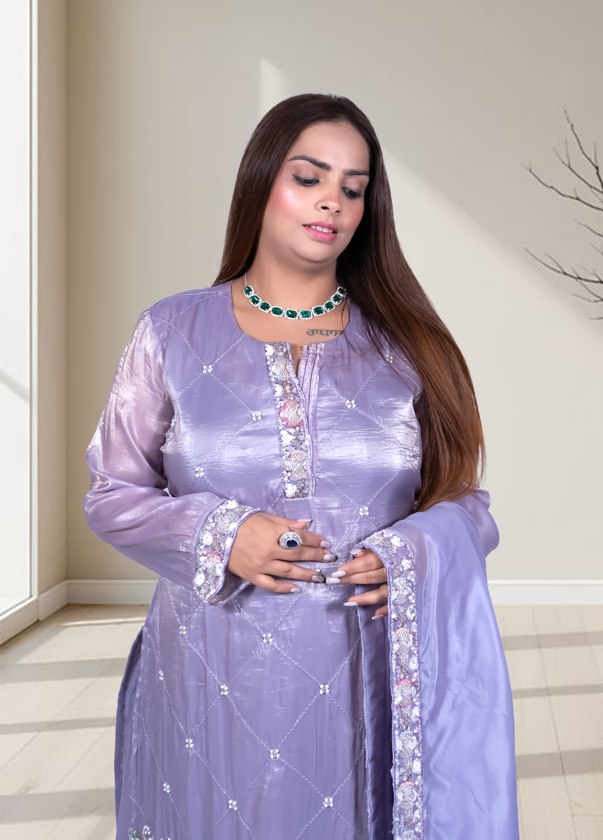 Woman wearing a light purple traditional outfit with intricate designs indoors.