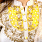 Close-up of a traditional outfit with yellow and gold embroidery.