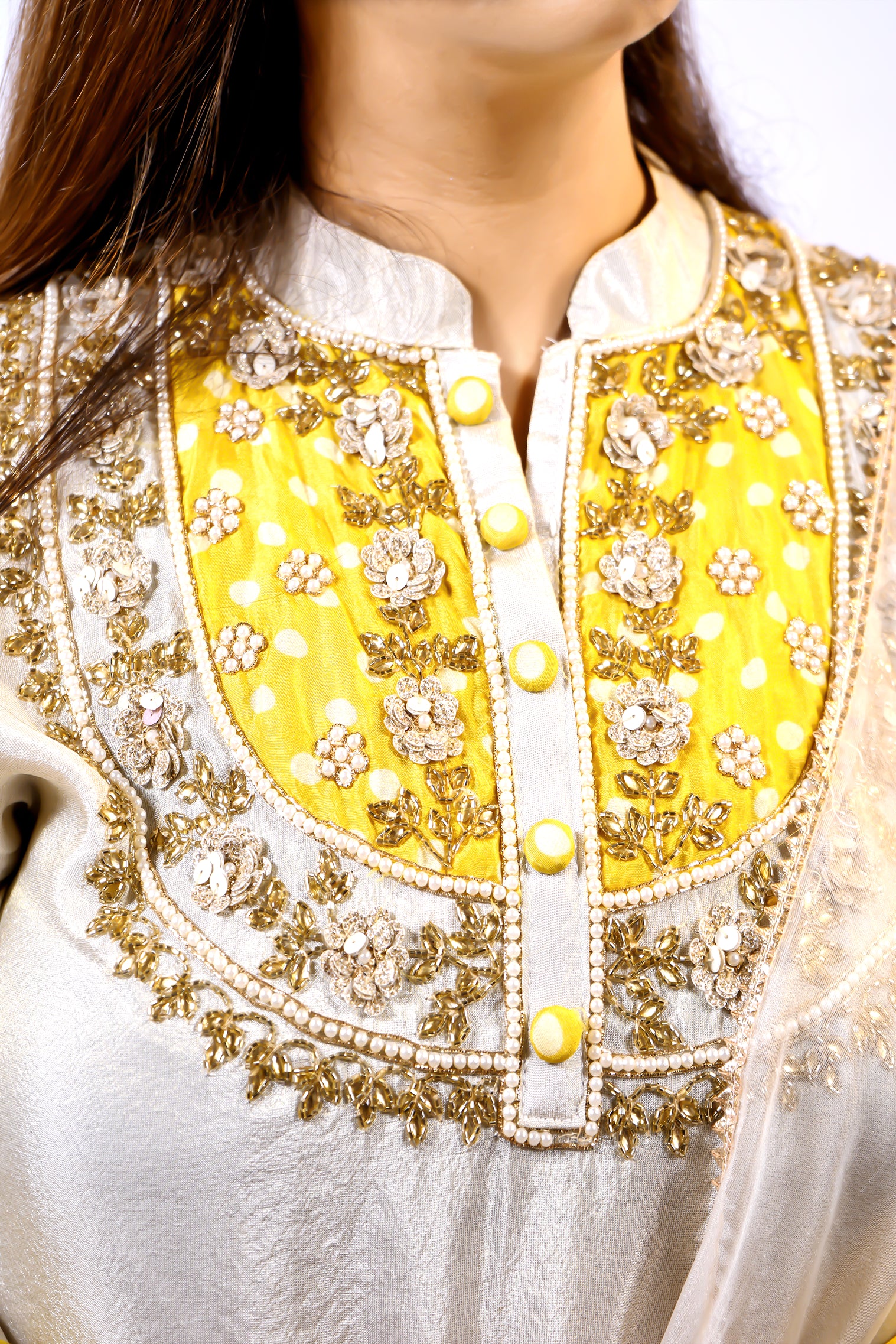 Close-up of a traditional outfit with yellow and gold embroidery.