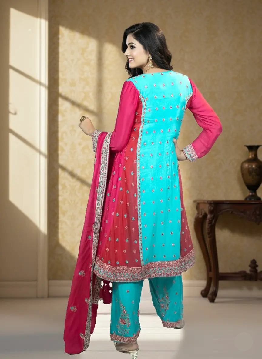 Woman wearing a turquoise and pink traditional outfit in a well-lit room.