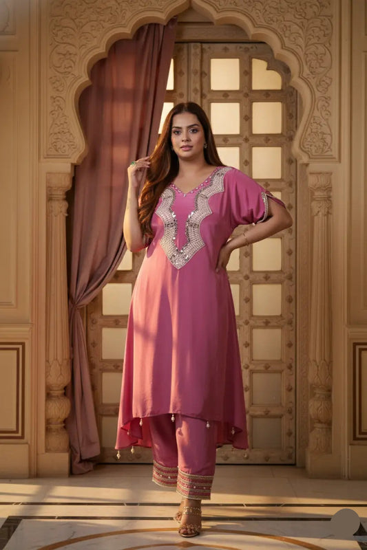 Woman in a pink traditional outfit standing in an ornate room.