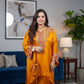 Woman in a mustard yellow traditional outfit standing in a living room.