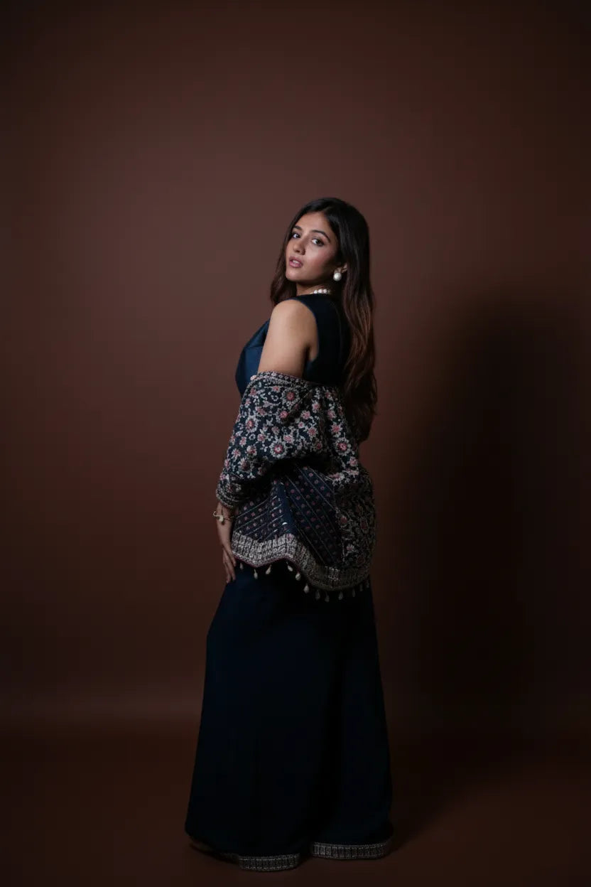 Woman wearing a dark blue patterned top and skirt against a brown background