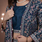 Woman wearing a traditional embroidered outfit with a blue top and dark blue skirt.