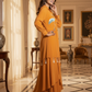 Woman in an orange dress standing in a luxurious room with decor elements.