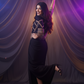 Woman in a black dress posing against a purple curtain